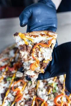 Chef hands holding slice of delicious gourmet pizza Stock Photos
