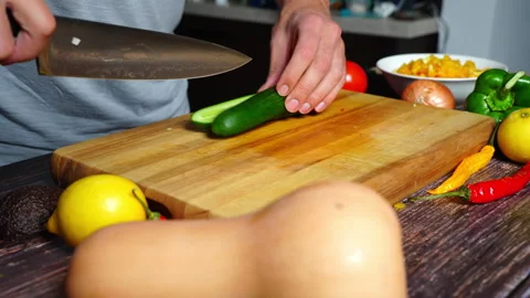 Chef hands in home kitchen cutting a cucumber on a wooden cutting board. Pr.. 库存影片 302303291