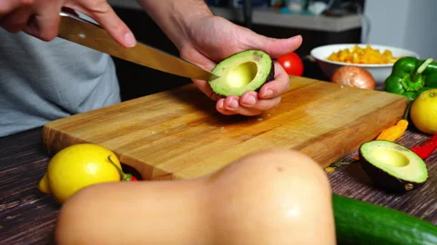 Chef hands in home kitchen cutting open an avocado, removing the pit and cu.. 库存影片 302305505