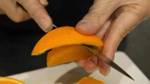 Chef Hands Peeling Fresh Orange Peel with Knife on Cutting Board Video stock 345292890