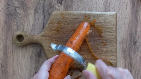 Chef hands peeling a raw orange carrot with a manual tool Stock Footage 336279568