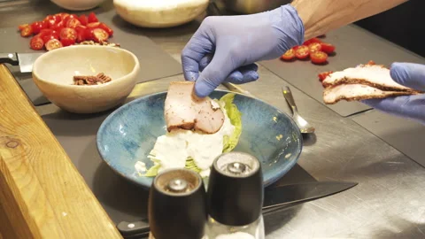 Chef hands preparing delicious salad with pastrami, tomatoes and pecans Stock Footage 135813392