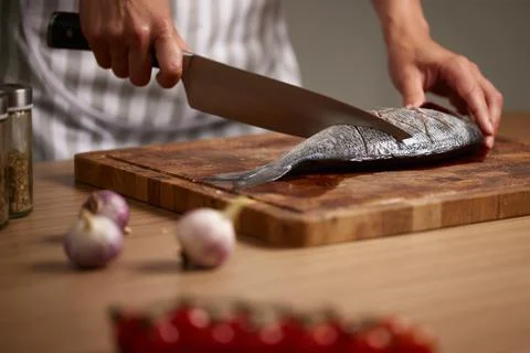 Chef hands preparing fresh fish on cutting board 写真素材