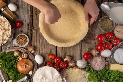 Chef hands puts the rolled dough into baking dish on wooden table with variet Stock Photos