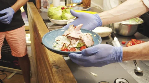 Chef hands serving plate with salad with pastrami and tomatoes on street market Stock Footage 135807852