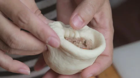 Chef hands shaping the dough with marinated pork chops inside to make a bun. Stock Footage 167781941