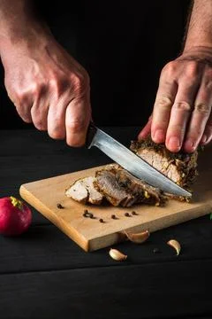 Chef hands slicing baked beef steak with knife on wood cutting desk. Top view Stock Photos