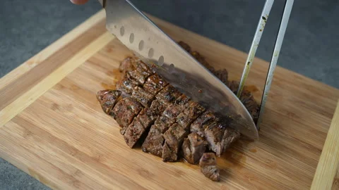 Chef hands slicing beef steak with knife on wooden cutting desk. Top view food Stock Footage 230255840