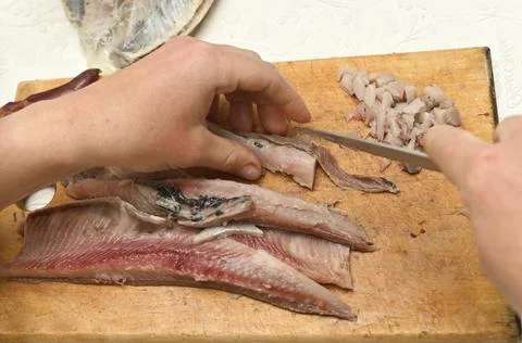 Chef hands slicing fresh herring fillet for meal. Stock Photos