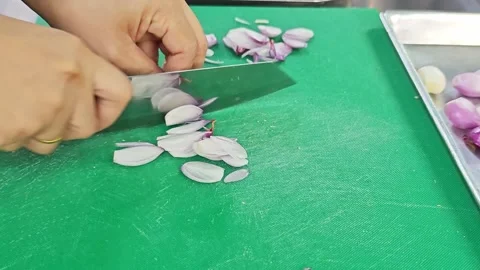 Chef hands slicing fresh shallots with a knife on a green cutting board. Stock Footage 344555006