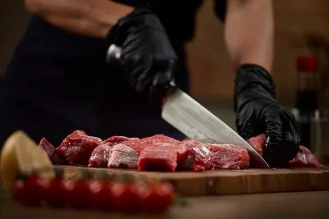 Chef hands slicing raw beef on cutting board Stock Photos