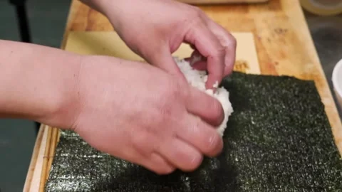 Chef hands spreading sticky white rice on nori seaweed sheet for sushi rolls. Stock Footage 333526217