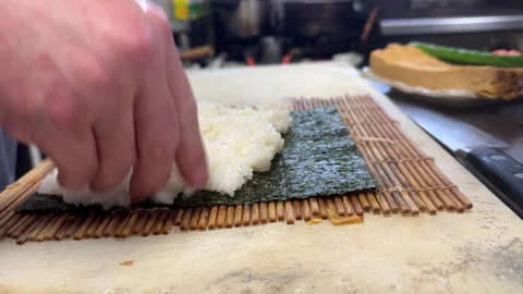 Chef hands spreading sushi rice on nori seaweed for makizushi roll, Japan Stock-Footage 343515314