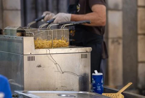 Chef hands using a commercial deep fryer to cook french fries in a restaura.. Stock Photos