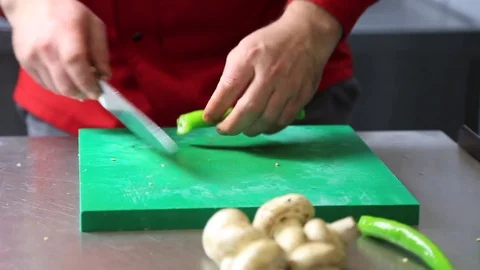 Chef hands using knife to cut green peppers on cutting board in kitchen Stock Footage 83643913