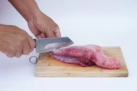 Chef hands using knife to slice raw pork lung on wooden cutting board. Concept o Stock Photos