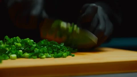 Chef hands wearing gloves chopping green onions on wooden board Stock Footage 319745216