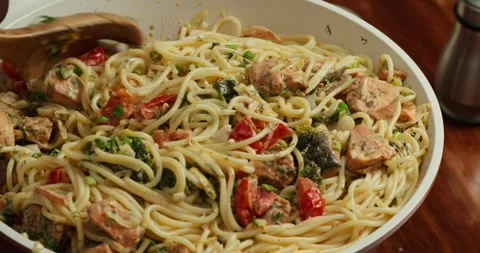 Chef he cook stirs the spaghetti with cherry tomato slices and spinach in creamy Stock Footage 317561114