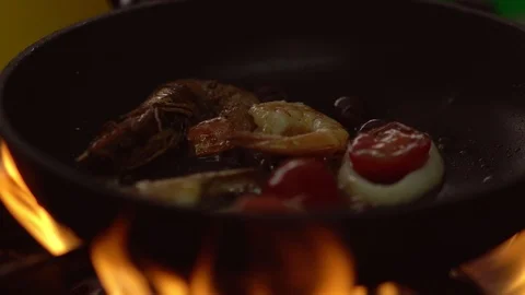 Chef heating seafood in a pan over open flames Stock Footage 115075521