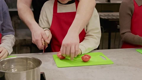 Chef Helping Child Slice Tomato during Culinary Class Stock Footage 339475531