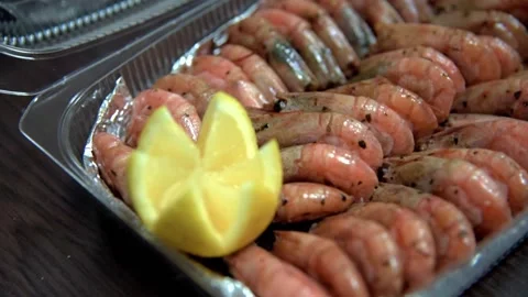 Chef with his hands in gloves puts fried shrimps and lemon in plastic box. HD Stock Footage 141744874