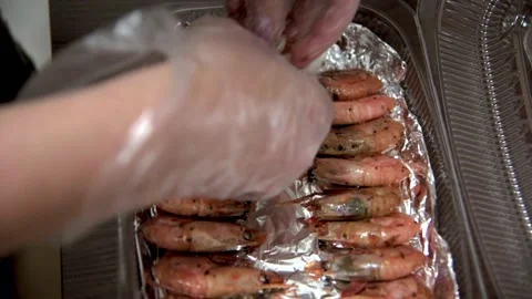 Chef with his hands in gloves puts fried shrimps in plastic box on foil. HD Stock Footage 141932174