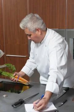 Chef Holding Carrots And Writing In Notebook Stock Photos