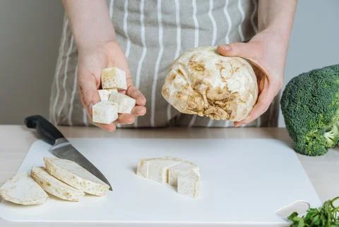 Chef Holding Celeriac Root and Diced Pieces on Cutting Board Foto stock
