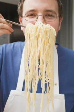 Chef holding up cooked spaghetti on spaghetti server Stock Photos