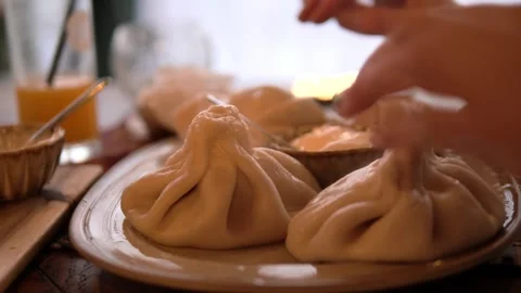 Chef holding georgian khinkali dumpling by doughy top knot, carefully eating Stock Footage 303433005