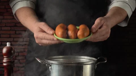 Chef holding green plate with boiled sausages over hot pan, demonstrating Stock Footage 331263657