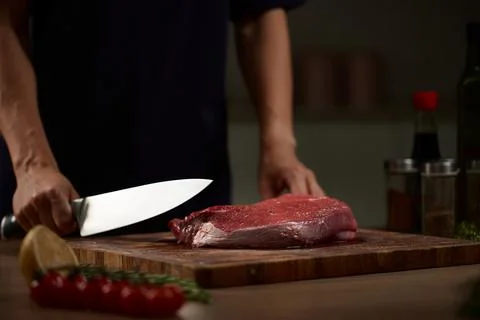 Chef holding knife preparing raw beef steak Stock Photos