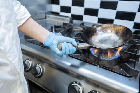 Chef holding a Pot metallic while heating up on the stove in a restaurant Stock Photos