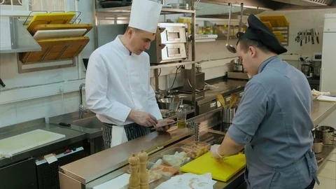 Chef holding tablet and instructing his trainee how to chop mushroom Vídeos de archivo 72322394