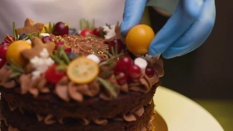 Chef holds a hand with fruit decorates a kumquat cake Stock Footage 119856953