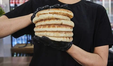 Chef holds stack of pita after baking in an electric oven 스톡 사진