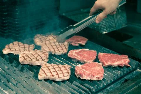 Chef in hotel or restaurant kitchen grilling pork for luxury dinner party wit Stock Photos