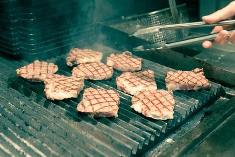 Chef in hotel or restaurant kitchen grilling pork for luxury dinner party wit Stock Photos