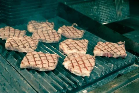 Chef in hotel or restaurant kitchen grilling pork for luxury dinner party wit Stock Photos