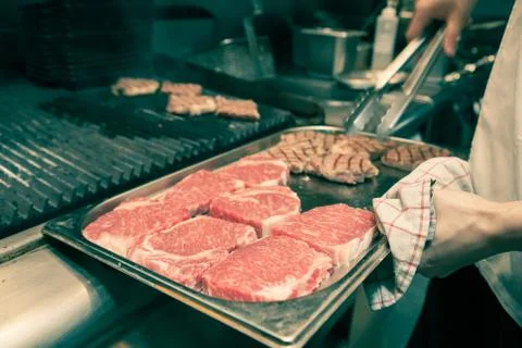 Chef in hotel or restaurant kitchen grilling pork for luxury dinner party wit Stock Photos