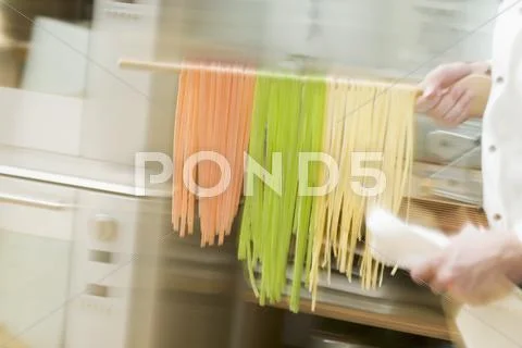 Chef hurrying through kitchen with ribbon pasta on wooden spoon Stock-Fotos