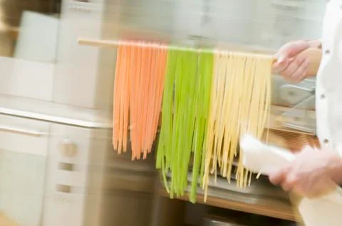 Chef hurrying through kitchen with ribbon pasta on wooden spoon Stock Photos