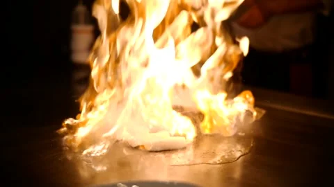 Chef igniting a massive fireball during hibachi cooking in a restaurant Stock Footage 328231475
