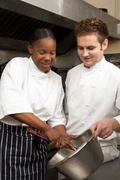 Chef Instructing Trainee In Restaurant Kitchen Stock Photos