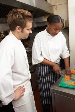 Chef Instructing Trainee In Restaurant Kitchen Stock Photos