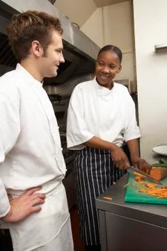 Chef Instructing Trainee In Restaurant Kitchen Stock Photos