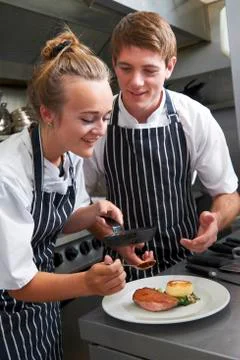 Chef instructing trainee in restaurant kitchen Stock Photos