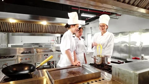 Chef instructor and two students tasting freshly cooked pasta in a kitchen. Video stock 313587285
