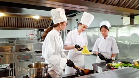 Chef instructor and two students tasting freshly cooked pasta in a kitchen Stock Footage 327122883