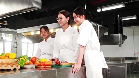 Chef instructor mentoring two young culinary students in a modern kitchen. Stock Footage 312192918